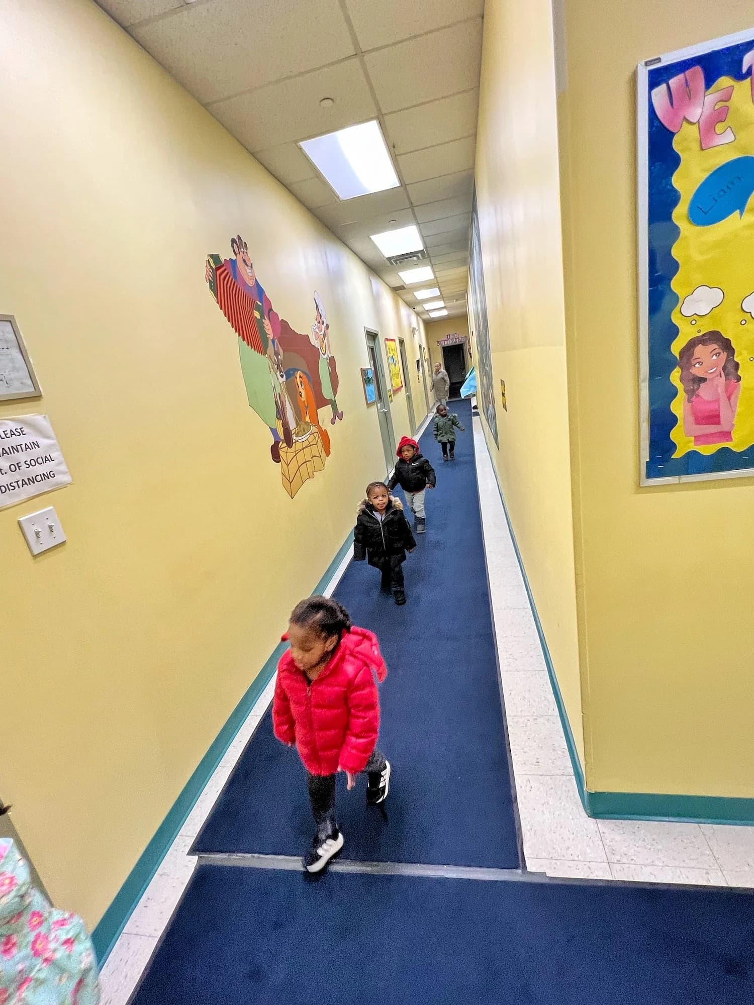 Children in winter coats walking through a colorfully decorated hallway