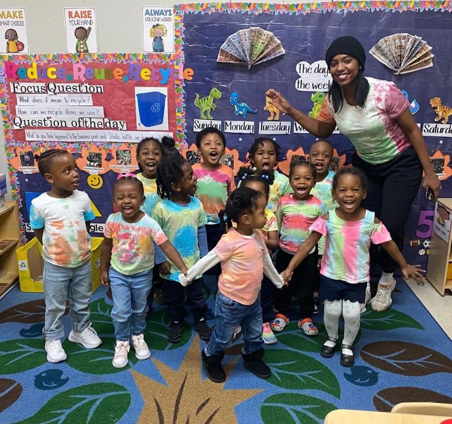 Pre-K children and teacher in tie-dye shirts during a classroom activity