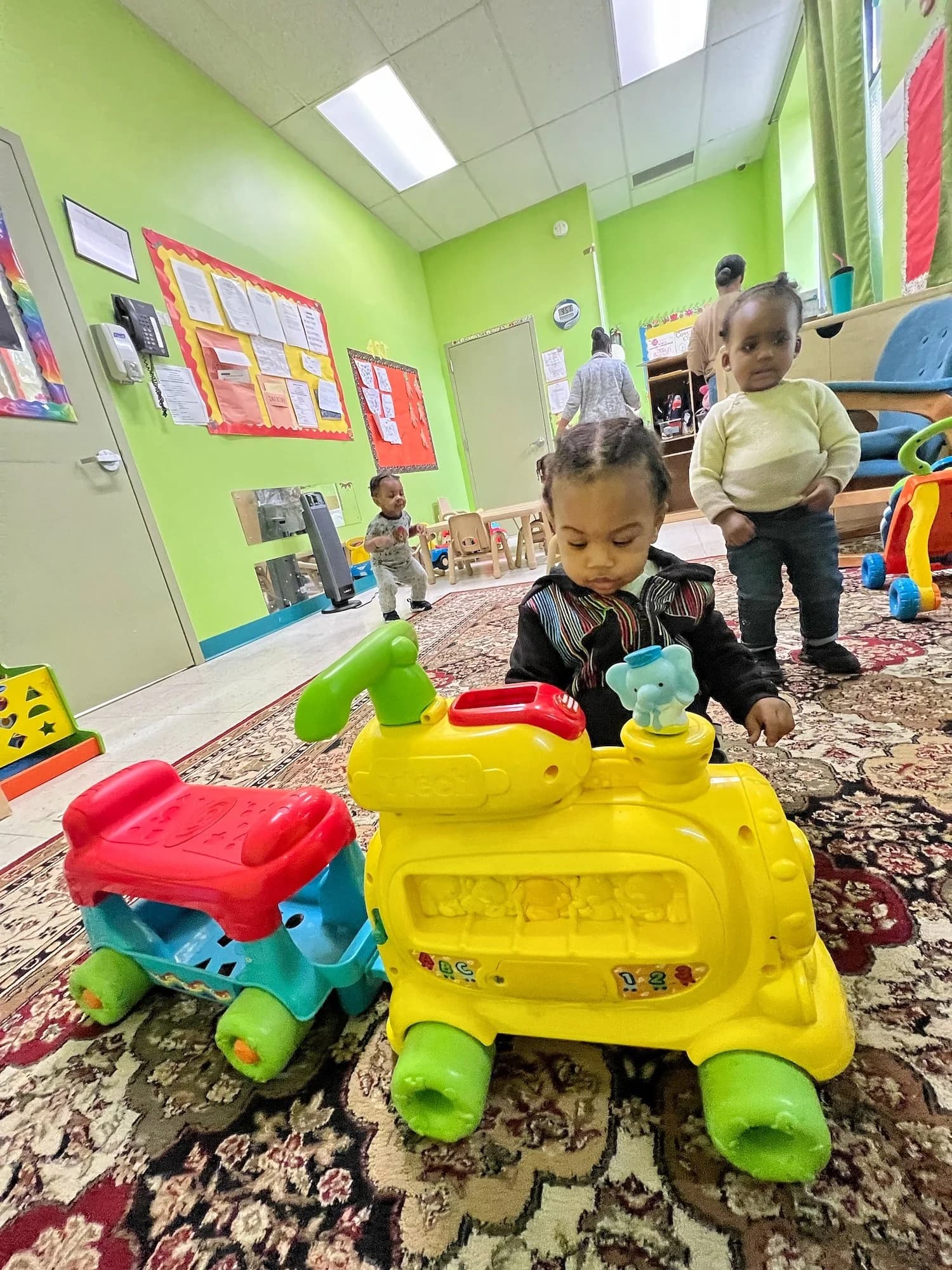 Toddlers playing with toy trains in the Einstein Daycare infant classroom